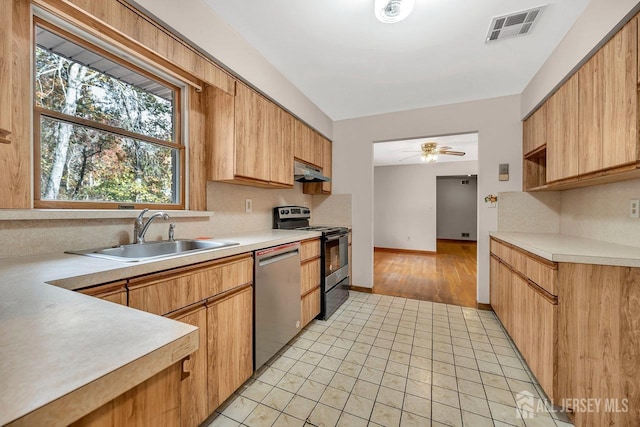 kitchen featuring under cabinet range hood, stainless steel appliances, a sink, visible vents, and light countertops