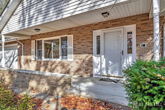 doorway to property with a garage, roof with shingles, and brick siding