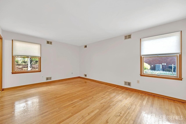 unfurnished room featuring light wood-style floors, baseboards, and visible vents