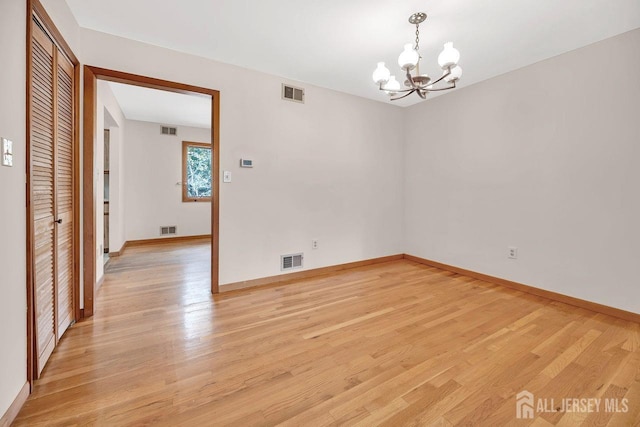 spare room with light wood-style floors, visible vents, baseboards, and an inviting chandelier