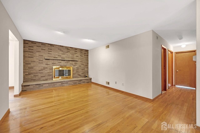 unfurnished living room featuring light wood-style floors, visible vents, a fireplace, and baseboards