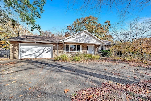 view of front of house with an attached garage, covered porch, aphalt driveway, and brick siding