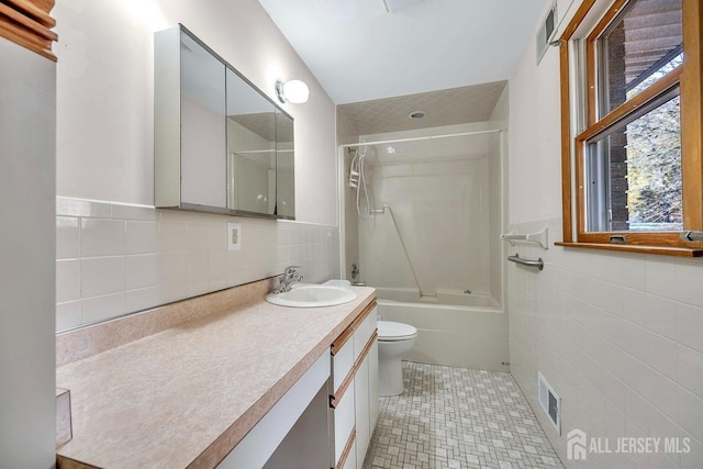 bathroom with visible vents, toilet, vanity, tile walls, and shower / bathing tub combination