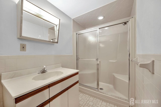 full bath with a wainscoted wall, a shower stall, and tile walls