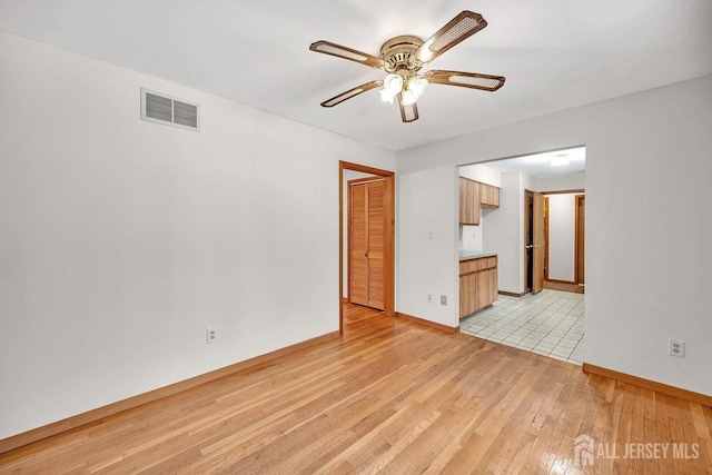 unfurnished room featuring baseboards, visible vents, ceiling fan, and light wood finished floors