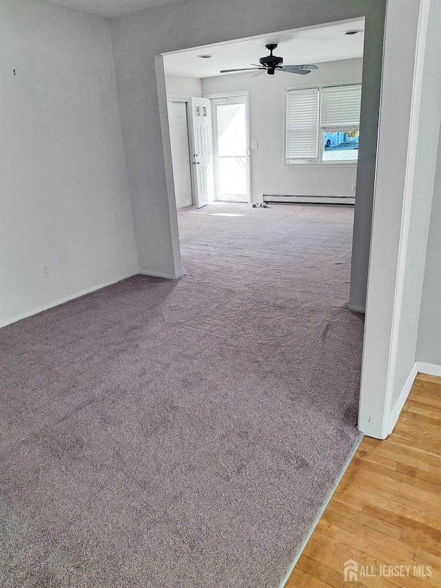 corridor with carpet flooring and a baseboard heating unit