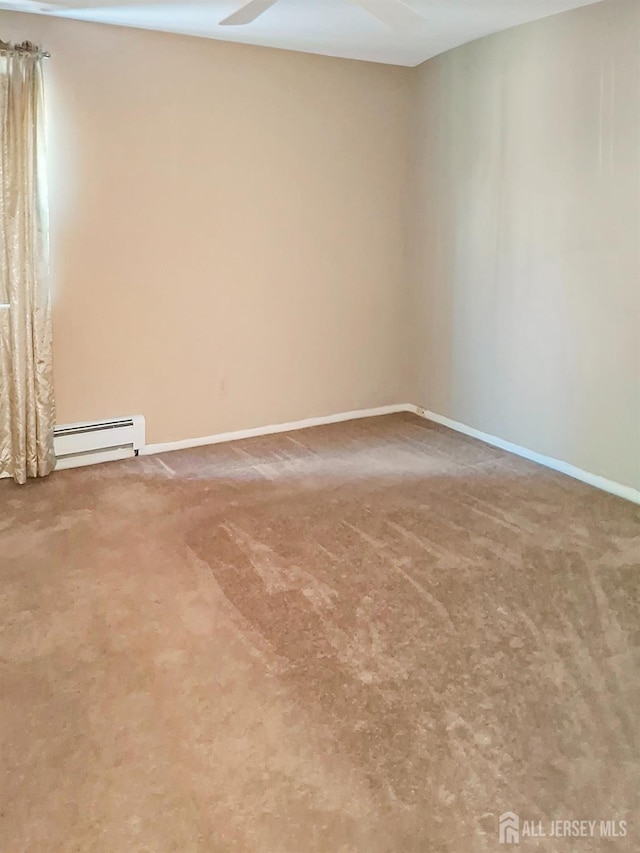 carpeted empty room featuring a baseboard heating unit