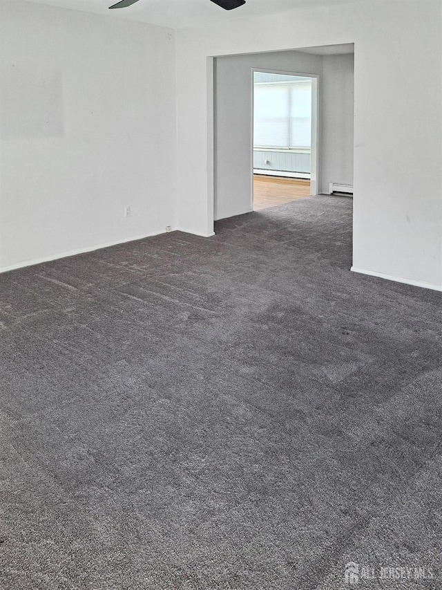 carpeted empty room featuring ceiling fan and a baseboard heating unit