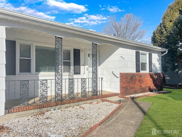 entrance to property featuring a yard and a porch