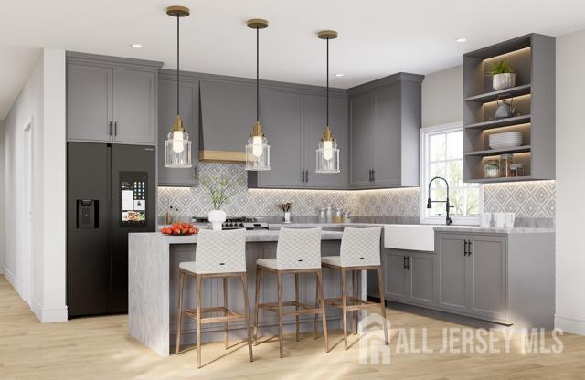 kitchen with gray cabinets, black fridge, light hardwood / wood-style flooring, and pendant lighting