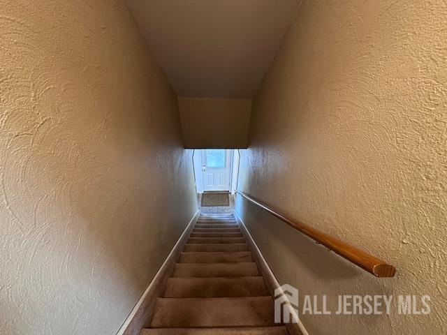 stairway featuring a textured wall and baseboards