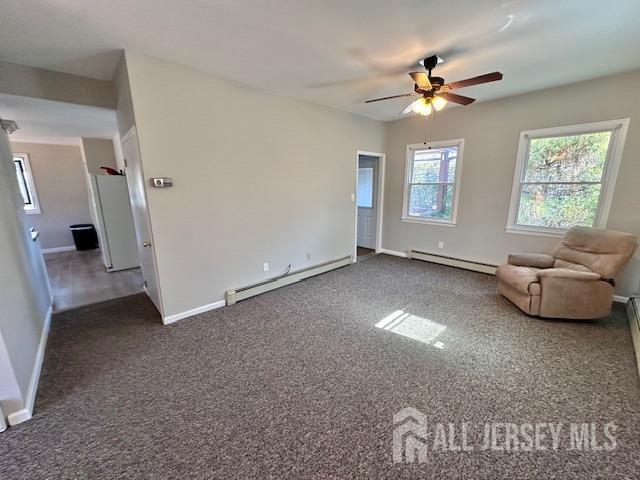 unfurnished living room with a baseboard radiator, baseboards, a ceiling fan, and carpet flooring