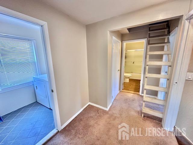 hallway featuring carpet floors, baseboards, and washer / clothes dryer