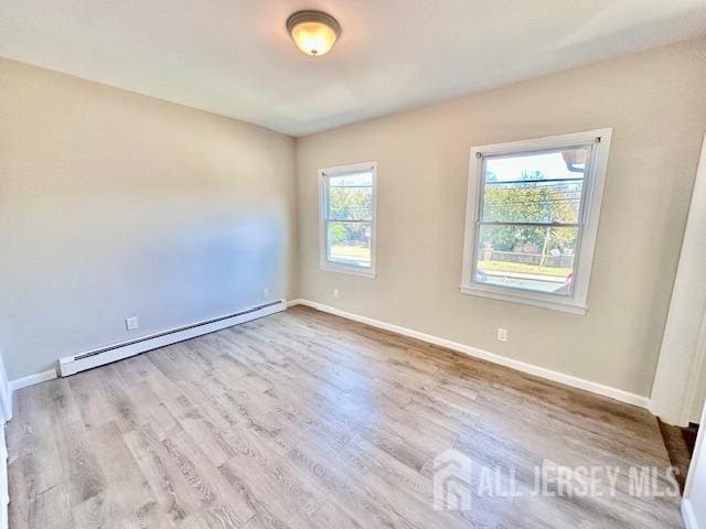 unfurnished room with a baseboard radiator, baseboards, and wood finished floors