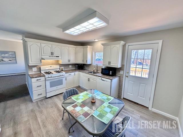 kitchen with a sink, white appliances, tasteful backsplash, and a wealth of natural light