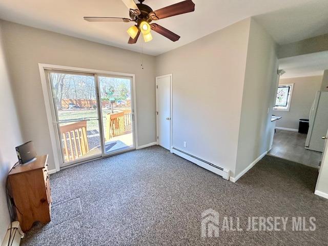 empty room with a wealth of natural light, a baseboard radiator, and carpet floors