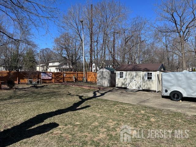view of yard featuring an outdoor structure, a shed, and fence