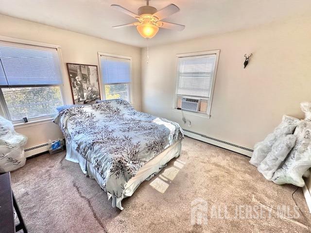 carpeted bedroom with ceiling fan, a baseboard heating unit, and cooling unit