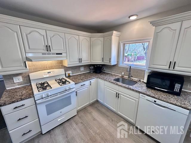 kitchen featuring white cabinets, under cabinet range hood, white appliances, and a sink