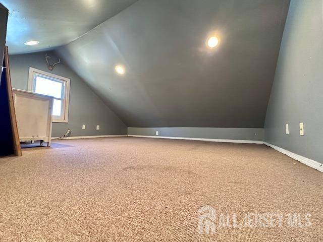 additional living space featuring vaulted ceiling, carpet flooring, and baseboards