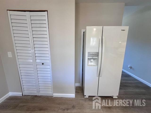 kitchen featuring baseboards, white fridge with ice dispenser, and wood finished floors