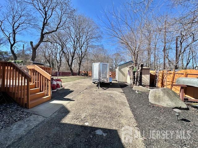 view of yard with a wooden deck, a fenced backyard, an outdoor structure, and a shed