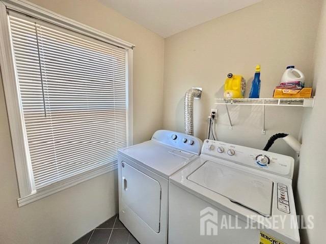 washroom featuring washer and dryer, dark tile patterned floors, and laundry area