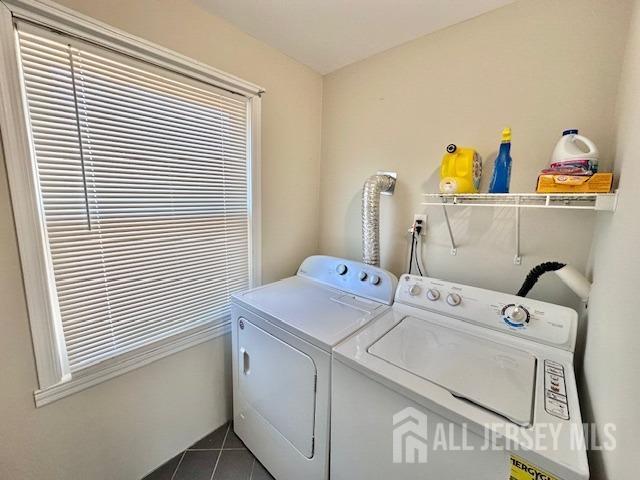 laundry room featuring washing machine and clothes dryer, dark tile patterned flooring, and laundry area