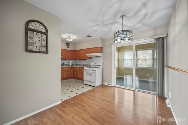 10 Nebraska Dr, Old Bridge, NJ 07747 - kitchen with white range with gas cooktop, under cabinet range hood, a chandelier, brown cabinets, and light wood-style floors