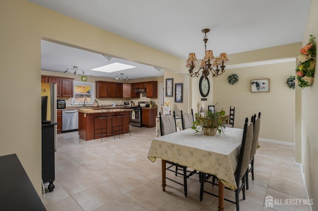 tiled dining room featuring sink, a skylight, and a chandelier