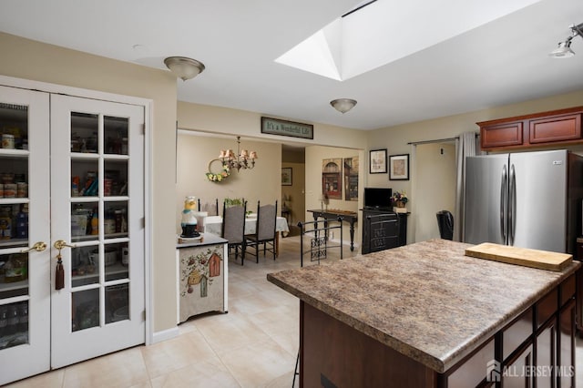 kitchen with light tile patterned flooring, an inviting chandelier, and stainless steel fridge