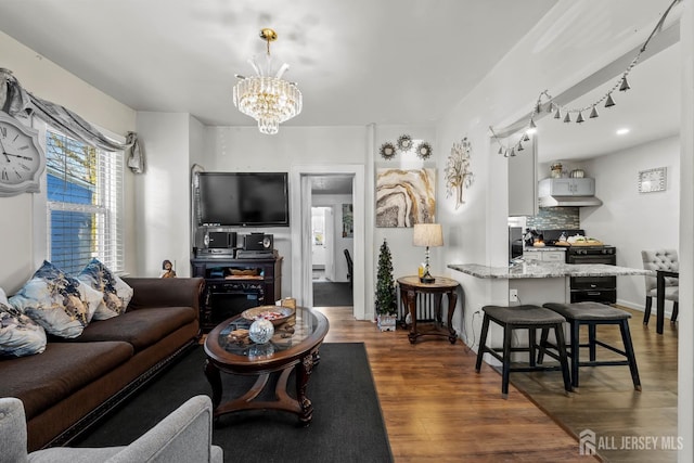 living area featuring a notable chandelier, wood finished floors, and baseboards