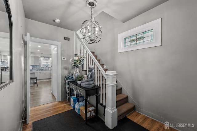 stairway featuring a notable chandelier, a healthy amount of sunlight, and wood finished floors