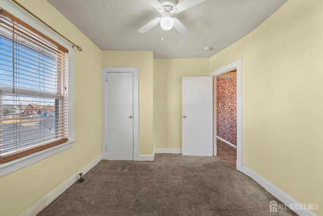 unfurnished bedroom with baseboards, carpet, a ceiling fan, and a textured ceiling