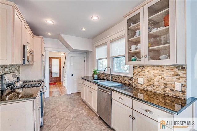 kitchen featuring tasteful backsplash, dark stone countertops, appliances with stainless steel finishes, and glass insert cabinets