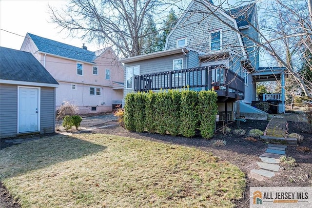 rear view of house featuring a gambrel roof, a lawn, and a deck