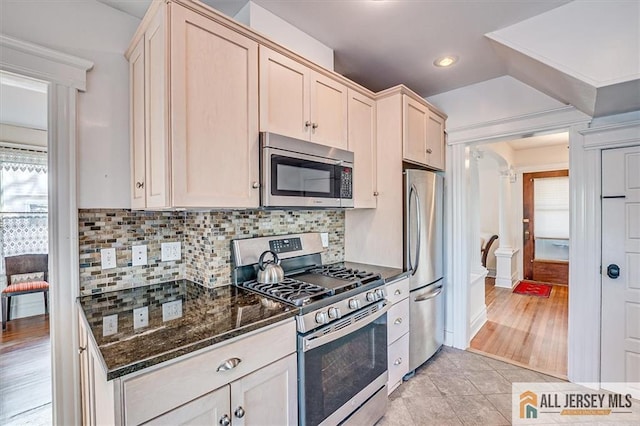 kitchen featuring dark stone counters, light tile patterned flooring, recessed lighting, stainless steel appliances, and backsplash