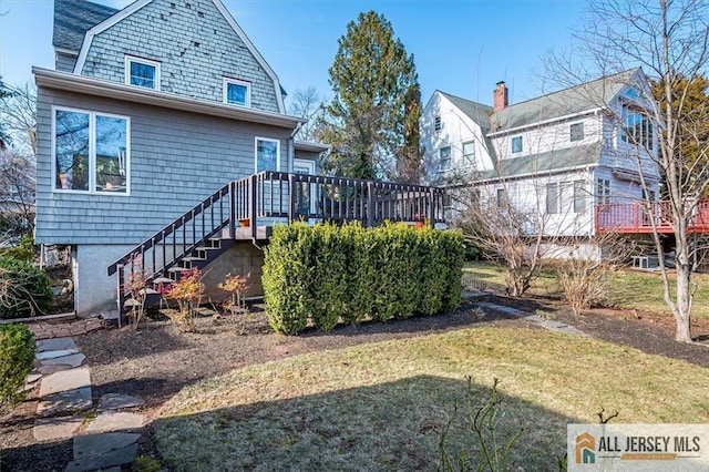 rear view of property with a lawn, a gambrel roof, stairs, and a deck