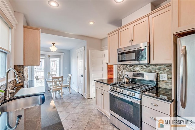 kitchen with a sink, tasteful backsplash, appliances with stainless steel finishes, and light brown cabinets