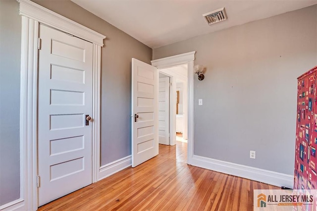 unfurnished bedroom with visible vents, baseboards, and light wood-style floors