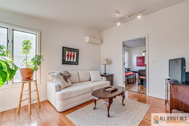 living room featuring baseboards, light wood-type flooring, and a wall mounted AC