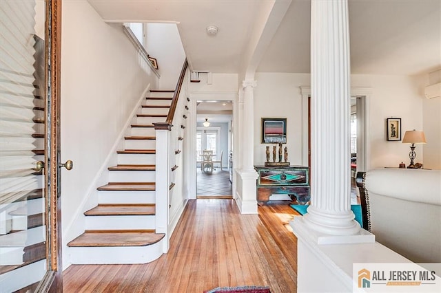 foyer featuring hardwood / wood-style floors, stairs, and decorative columns