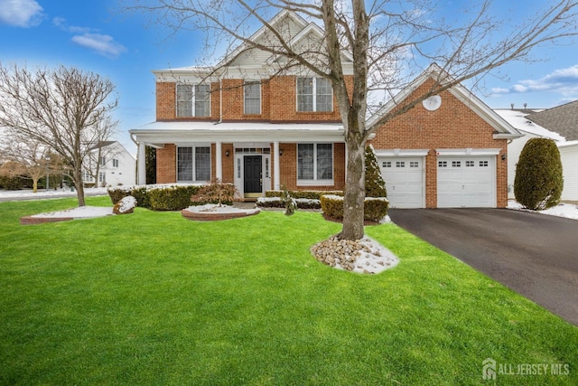 view of front facade with brick siding, a front lawn, driveway, covered porch, and a garage