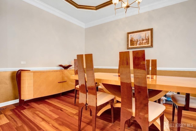 dining room with baseboards, an inviting chandelier, crown molding, and wood finished floors