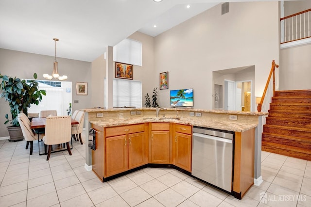 kitchen with a kitchen island with sink, stainless steel dishwasher, brown cabinets, light stone counters, and pendant lighting