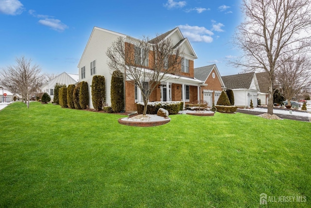 view of front of property with a garage, driveway, brick siding, and a front lawn