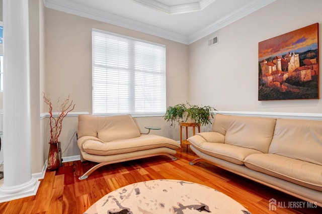 living area featuring ornamental molding, visible vents, decorative columns, and wood finished floors