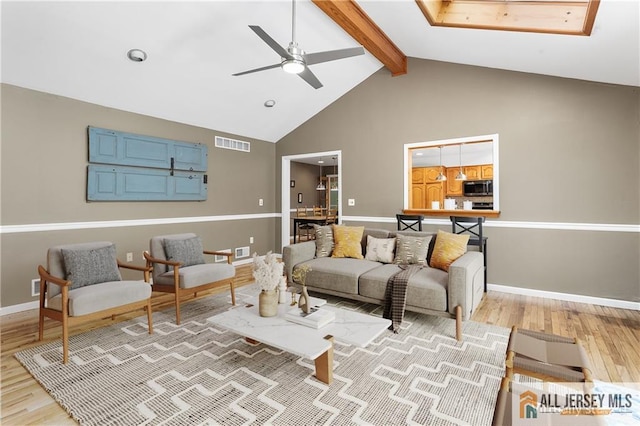 living room featuring ceiling fan, light hardwood / wood-style flooring, beamed ceiling, and high vaulted ceiling