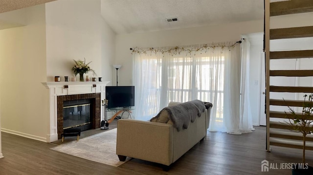 living room with dark wood-style flooring, a fireplace, visible vents, and vaulted ceiling