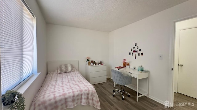 bedroom featuring baseboards, a textured ceiling, and wood finished floors